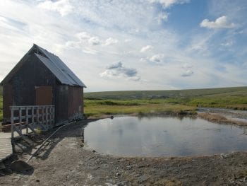 Image of a bathhouse and outdoor hot spring at Serpentine Hot Springs, Alaska